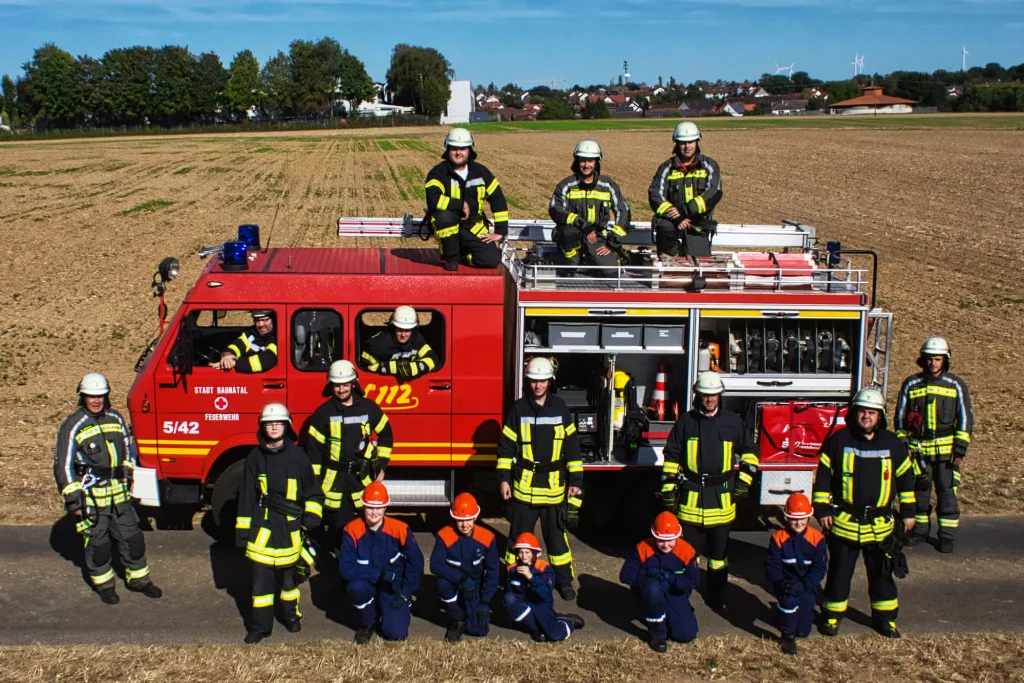 Feuerwehrfahrzeug der Freiwilligen Feuerwehr Baunatal-Hertingshausen mit Einsatzabteilung und Jugendfeuerwehr davor.