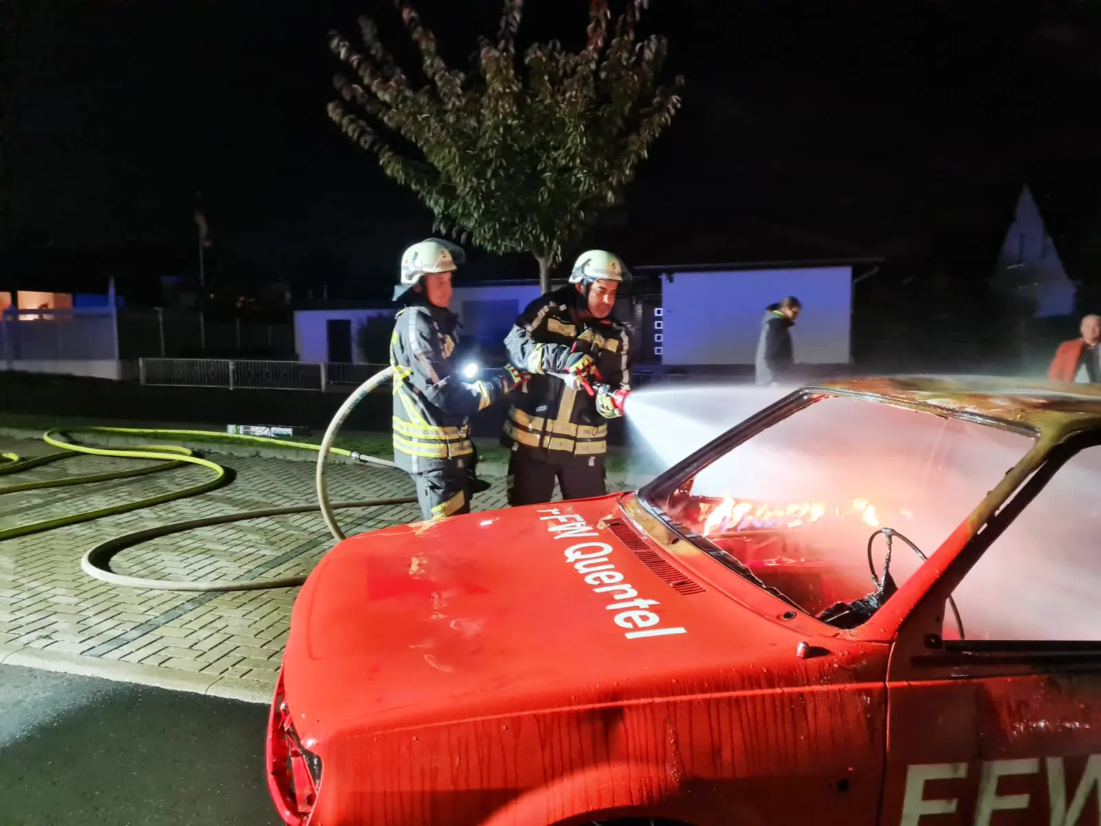 Feuerwehrleute der Freiwilligen Feuerwehr Hertingshausen üben das Löschen eines roten Autos.