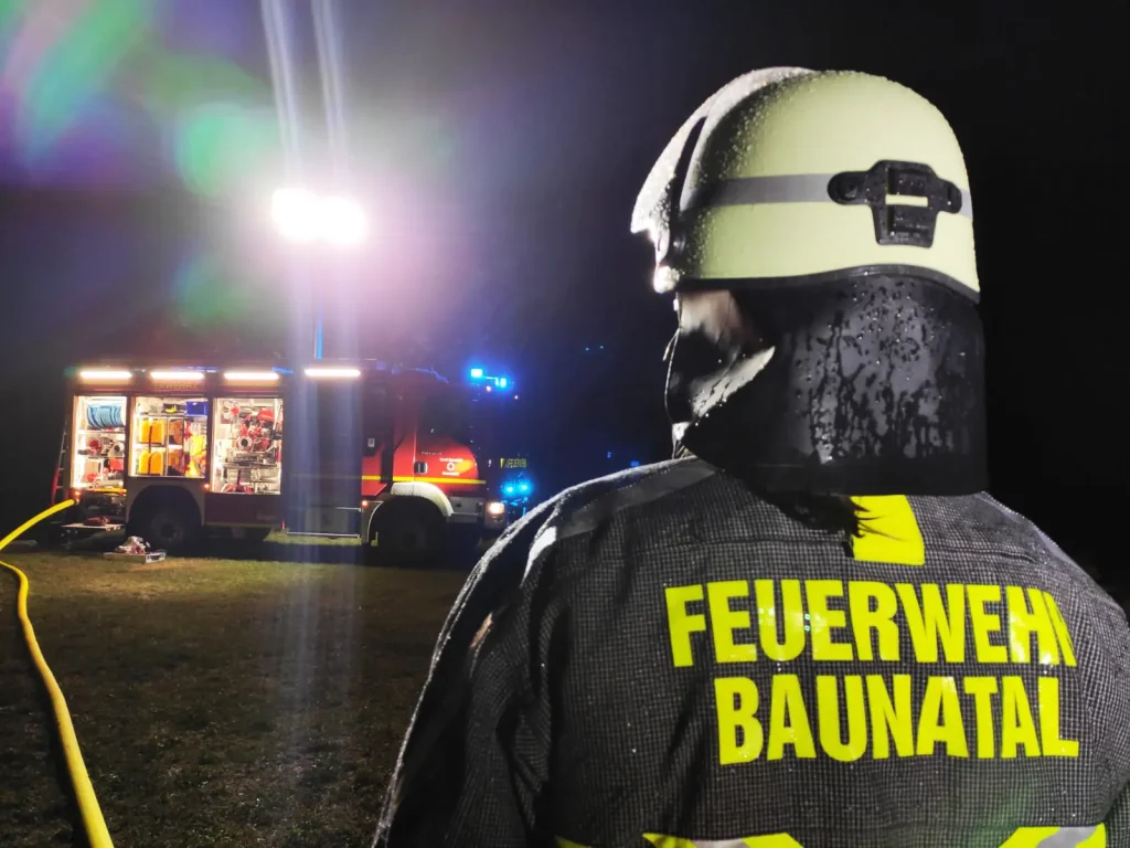 Feuerwehrmann der Feuerwehr Baunatal bei einem nächtlichen Einsatz mit Scheinwerferbeleuchtung.