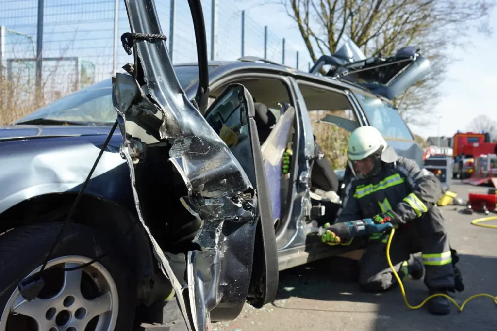 Feuerwehrleute der Freiwilligen Feuerwehr Hertingshausen schneiden bei einer Übung ein Auto mit schwerem Rettungsgerät auf.
